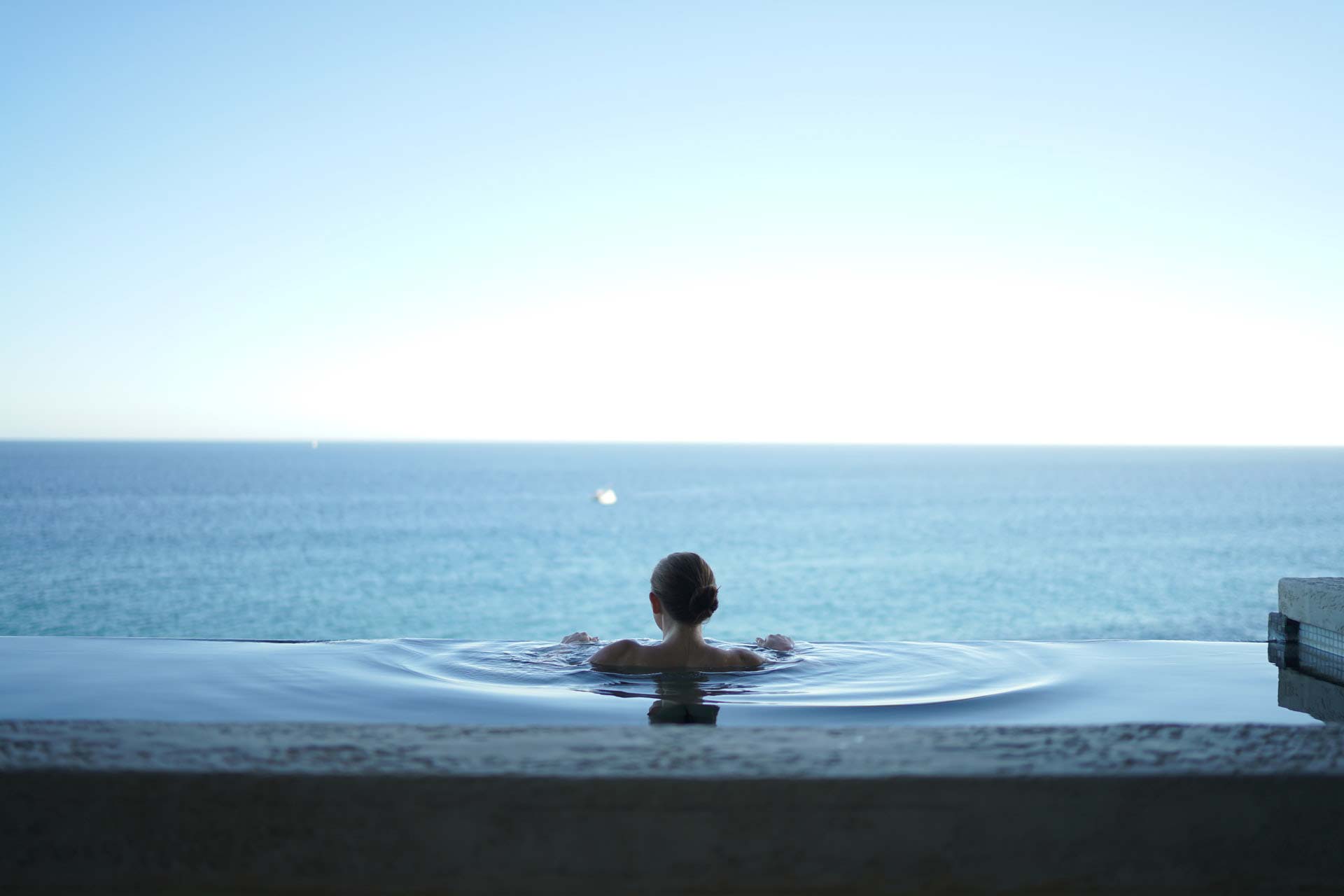 a woman In an overflow pool, overlooking the water