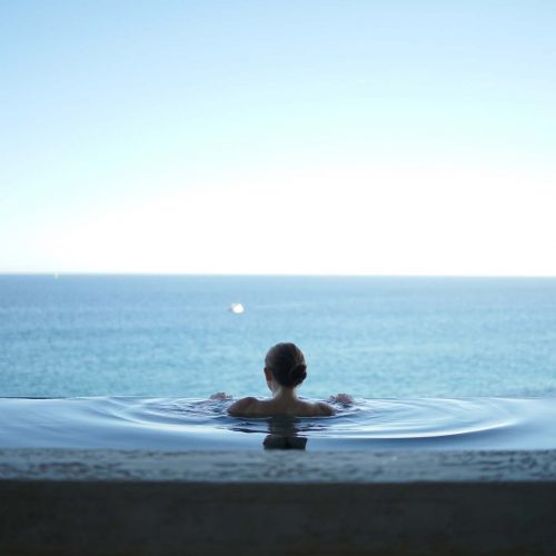 a woman In an overflow pool, overlooking the water