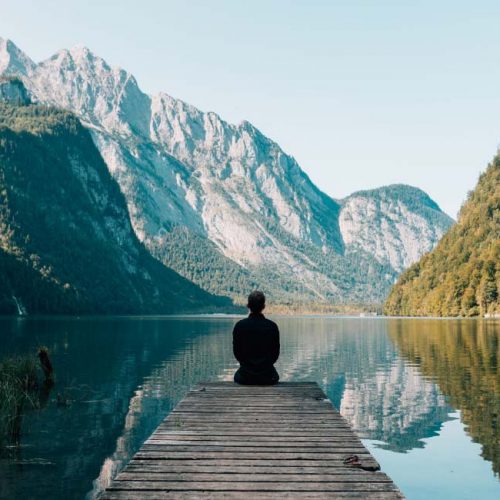 a person sitting looking at the lake and mountains